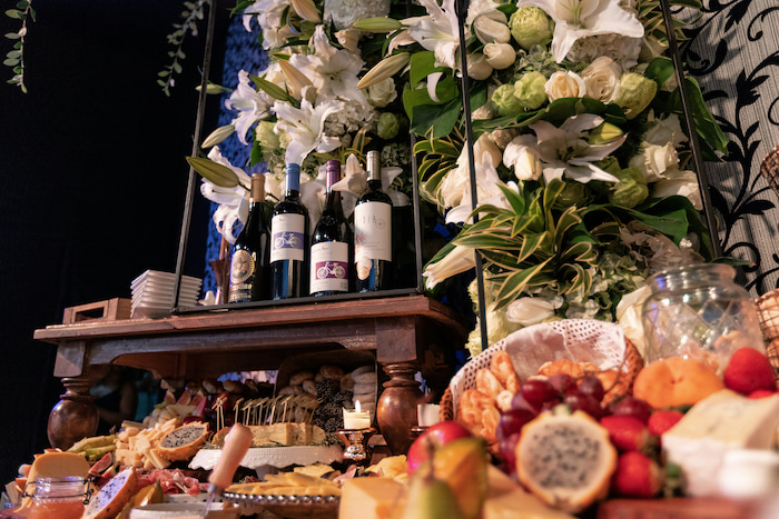 A beautiful array of desserts laid on a white table with a party going on in the distance