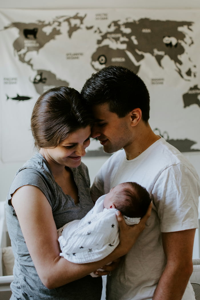 A couple embrace while the mother holds and looks lovingly at their newborn