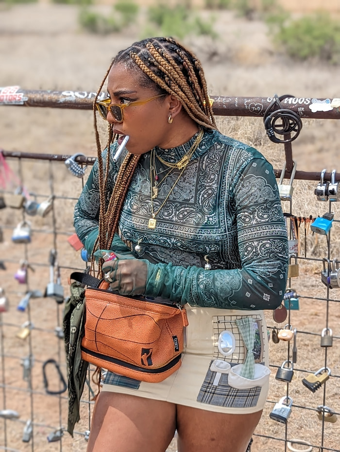 A model reaching into her purse for a lighter while a cigarette hangs from her mouth